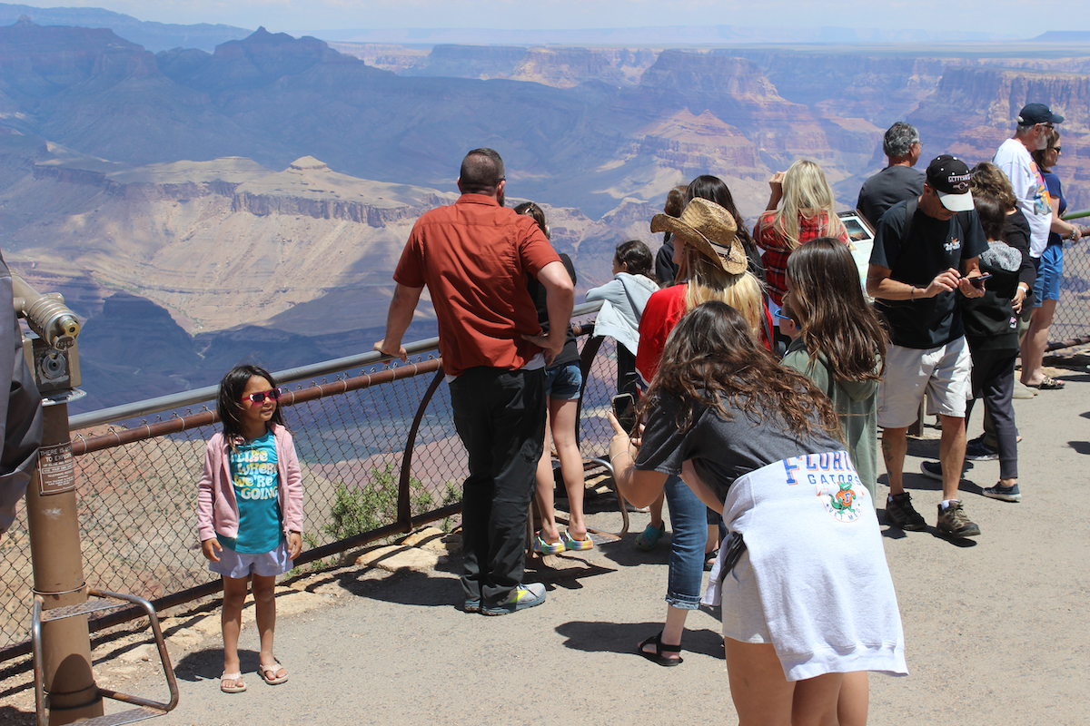 Oldest sister taking picture of the youngest sister while middle sister looks on.
